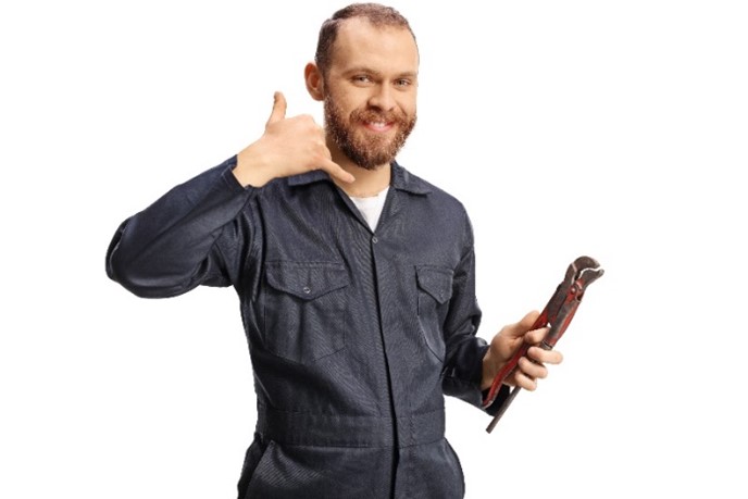 A male plumber in a uniform holding pliers and gesturing a “call me” sign with his hand, encouraging homeowners to contact his company in Carol Stream, IL.