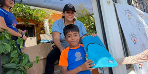 Volunteers handing a backpack to a young boy at a Backpacks of Hope giveaway