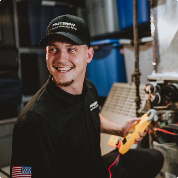 Smiling Precision Today technician using a multimeter on a water heater
