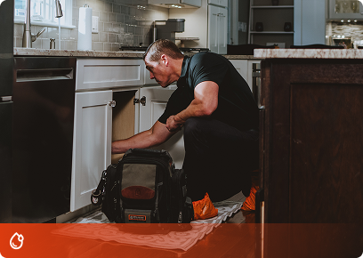 Precision Today plumber working on pipes under a kitchen sink